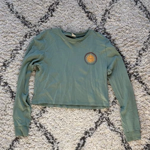 långärmad topp - Grön/olivgrön långärmad tröja som är lite cropped, med ett tryck bak på ryggen! Från urban outfitters!