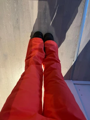Röda täckbyxor med dragkedja - Säljer ett par korall färgade skidbyxor,  dragkedja nertill och spännbar midja. Endast använt 1 vecka! 