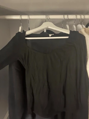 Svart långärmad topp från Nelly - En svart långärmad topp från Nelly med en snygg, något vid urringning. Toppen har en enkel och stilren design som passar till många olika outfits. Jättebra skick.