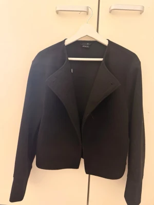 Svart kavaj från Mango - Stilren svart kavaj från  gina tricot med öppen front och klassisk krage. Rak passform och långa ärmar, perfekt för en trendig och clean look. Materialet känns mjukt och ger en snygg siluett.