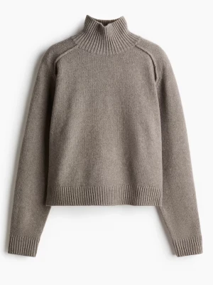 Polo stickad tröja - Säljer en beige stickad tröja med hög ribbad krage och långa ärmar. Tröjan har en boxig, något croppad passform och ribbade muddar vid ärmslut och nederkant. Perfekt för lager på lager och enkel att styla till jeans.