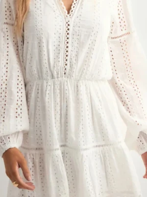 Vit broderad klänning med volang - Superfin vit klänning med broderade detaljer och volanger. Klänningen har v-ringning, långa ärmar och en luftig passform. Perfekt för varma dagar och har en romantisk känsla med sina spetsinslag.