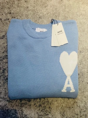 Ljusblå Ami Paris tröja - Riktigt fet Ami tröja i ljusblå med vit logga på bröstet. Tröjan är storlek S och skicket är mycket bra, utan  några defekter. Perfekt för dig som söker en stilren look med en gnutta elegans. Hör gärna av dig om funderingar som mått, pris, bilder etc. Så löser vi! 😁