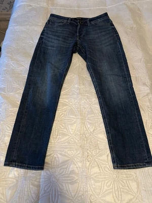 Jack & Jones - Klassiska blå Jack & Jones jeans med rak passform och fem fickor. Jeansen har en tidlös look med subtila slitningar och är tillverkade i robust denim. Perfekta för dig som gillar en enkel och clean stil. Pris kan diskuteras.
