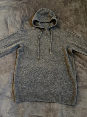 Stickad hoodie - En stickad mörkgrå hoodie i nytt skick. Storlek L. Hör av er vid frågor och funderingar. Fraktar snabbt✅