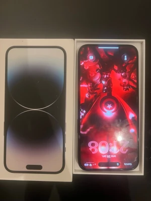 iPhone 14 Pro max 128gb space grey  - Snygg iPhone 14 Pro i svart färg med stilren design och glasbaksida. Telefonen har tre kameror på baksidan och levereras i originalförpackning. Perfekt för dig som vill ha en kraftfull och modern smartphone från Apple.