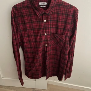 Röd rutig skjorta från J.Lindeberg - Snygg röd och svart rutig skjorta från J.Lindeberg i storlek M, slim fit. Modellen är va 180cm. Hör av dig vid funderingar 