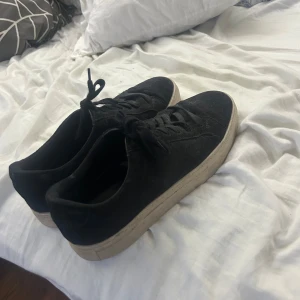 Svarta sneakers från Vagabond i mocka - Svarta sneakers från Vagabond med ovandel i mjuk mocka och klassisk snörning. Skorna har en vit, platt sula som ger en snygg kontrast mot det svarta. Perfekta för dig som gillar stilrena och enkla skor med en modern touch.