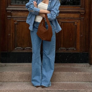 Jeans med lång midja  - De här jeansen har en låg midja och en dragkedje- och knappstängning. De har en femficksdesign och vida ben.