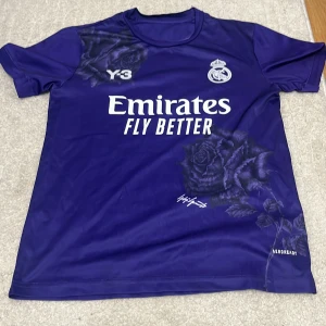 Real Madrid x Y-3 Adidas fotbollströja S - Säljer en limited edition Real Madrid x Y-3 fotbollströja från Adidas i mörklila. Tröjan har korta ärmar, blommigt rosmönster, klubbmärke och 'Emirates Fly Better' tryck på bröstet. Tillverkad i lätt funktionsmaterial (AEROREADY) och slim fit.