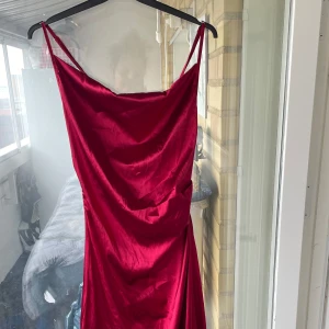 Röd långklänning från SHEIN i satin - Snygg röd långklänning från SHEIN i glansigt satinliknande material. Klänningen har tunna axelband, draperad urringning och en elegant, släpande siluett. 