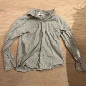 Ljusgrå skjorta från Tiger of Sweden - Snygg ljusgrå skjorta från Tiger of Sweden i bomull. Klassisk krage, knäppning framtill och långa ärmar med manschett. Enkel och stilren design som passar till många olika looks.