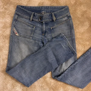 Blå jeansbyxor från Diesel - Säljer ett par klassiska blå jeansbyxor från Diesel med raka ben och stora framfickor. Byxorna har en snygg tvättad look och en liten Diesel-logga på vänster ficka. Perfekta för dig som gillar en avslappnad och stilren vibe.