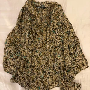 Mönstrad blus från Zara i tunnt tyg - Säljer en luftig och oversized blus från Zara med abstrakt mönster i beige, brunt och inslag av grönt. Blusen har långa, vida ärmar och knytning vid halsen. Jag har sytt vid v - ringningen pga den var super djup. Syns knappt på nära håll och smälter in bra. I storlek M men passar mig som är S.