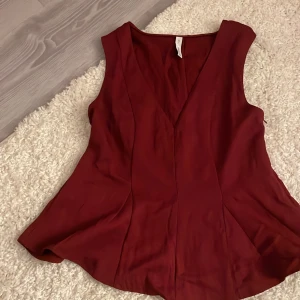 Vinröd ärmlös topp från MNG - Säljer en vinröd ärmlös topp från MNG med v-ringning och lätt utsvängd passform. Toppen har en stilren look och är tillverkad i ett mjukt, slätt tyg som faller snyggt. Perfekt för dig som gillar enkla men snygga plagg.