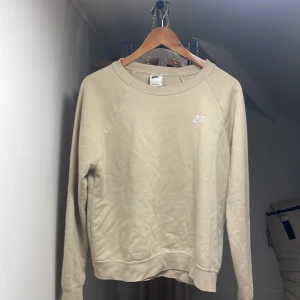 Beige sweatshirt från Nike, M - Snygg beige sweatshirt från Nike med klassisk logga broderad på bröstet.  Den har aldrig kommit till användning och måste sälja nu för jag ska flytta💕 vill man ha den stryken så skriv de till mig 💕💕