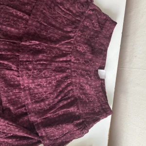 Vinröd kjol från Lindex - Supersöt vinröd kjol från Lindex i storlek 146/152. Kjolen är täckt av vacker spets med blommigt mönster och har en mjuk, fodrad insida. Perfekt för dig som vill ha en romantisk och trendig look med extra detaljer.