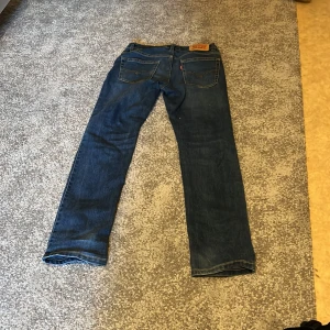 Levi's 511 blå slim fit - Säljer ett par klassiska blå Levi's 511 jeans med rak passform. Jeansen har fem fickor, Levi's ikoniska läderpatch bak och röda logotag på bakfickan. Tillverkade i slitstarkt denimtyg som ger en tidlös look. Strl 12a för barn obs passform som står i beskrivning är ej 30