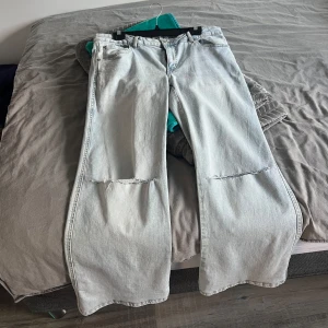 Bootcut jeans i ljus denim från 157 - Bootcut jeans i ljusblå denim från 157 med slitna detaljer vid knäna. Klassisk femficksmodell med lock på bakfickorna och knappstängning. Snygg 90-talsvibe och bredare benslut. Perfekta för dig som gillar retrostil. Jeansen är helt nya men har inte kvar prislappen på. Aldrig använda. Säljer för dom är för stora (fick dom i present men fel storlek)