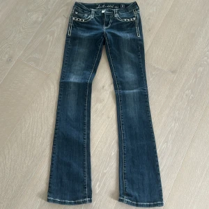 L.A. Idol jeans  - Mörkblå jeans från L.A. Idol med vita kontrastsömmar, strassdetaljer på fickorna och broderade bakfickor. Bootcut-modell med låg midja och snygg tvätt. Perfekta för dig som gillar extra detaljer och bling. Skit snygga❣️storlek 26 men kan vara 23