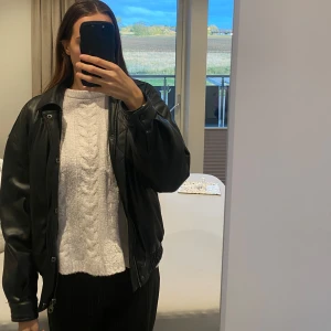 Svart bomberjacka från Black Squad XS - Säljer en svart bomberjacka från Black Squad i storlek XS. Jackan har klassisk bombermodell med resår i midjan och vid ärmslut, dragkedja och knappar framtill. Tillverkad i ett glansigt syntetmaterial