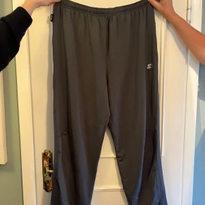 Grå träningsbyxor från Starter - Mörkgrå träningsbyxor från Starter med elastisk midja och en liten logga på vänster lår. Byxorna har en smal passform och en bakficka med dragkedja. Perfekta för chill eller träning.