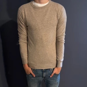 Beige cashmeretröja John Henric S - Säljer en stilren beige stickad tröja från John Henric i 100% kashmir.  Köpte för ungefär 2200kr, mitt pris, 1199 eftersom tröjan är i väldigt fint skick utan några defekter. Hör av er vid frågor eller funderingar!