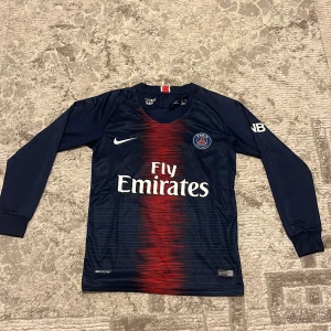 PSG Neymar Jr långärmad matchtröja #10 - Paris Saint-Germain långärmad fotbollströja från Nike, säsong 2018, med Neymar Jr och nummer 10 på ryggen. Marinblå med röd grafisk rand i mitten, vita tryck och PSG-emblem på bröstet. Materialet är lätt och andas, perfekt för träning. Ni can rekommendera vilken pris ni vill ha den för.
