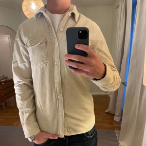 Beige Overshirt Levi’s  - Säljer denna sjukt snygga Overshirten från Levis⭐️ Färgen är beige och storleken är S✅ Den har inga defekter och skicket är utomordentligt🙌🤝 Sjukt najs passform och passar perfekt till hösten🍁🙌 Tveka inte på att höra av er dig vid minsta fråga eller fundering😊