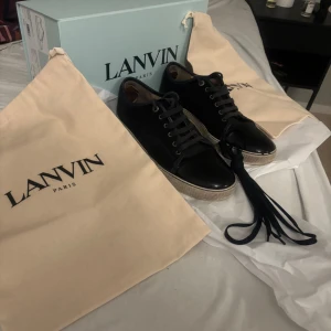 Lanvin mörkblå sneakers i skinn - Snygga Lanvin sneakers i mörkblått kalvskinn med lackad tå och klassisk snörning. Skorna har en vit gummisula och stilren design, perfekt för dig som gillar exklusiva detaljer. Kommer med originalbox och dustbags från Lanvin Paris.