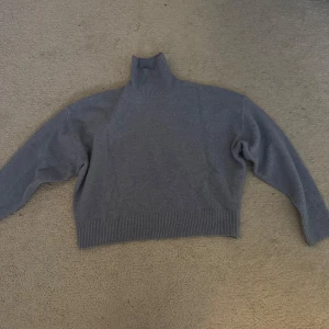 Blå/grå polotröja i mjuk ullmix - Säljer en stilren grå polotröja med hög krage och långa ärmar. Perfekt nu till hösten! 🍁🍂 Anvönd max 2 ggr så den är i nyskick.