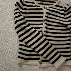 Randig kofta från MNG med guldknappar - Snygg randig kofta från MNG i marinblå och vitt med guldiga knappar framtill. Koftan är stickad och har långärmad modell med rund halsringning. Använt fåtal gånger. ‼️Kan tänka mig att sänka priset om det är rimligt. ‼️