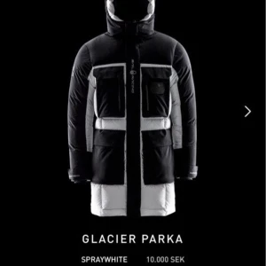Sail Racing Glacier parka jacka - Säljer en Sail Racing Glacier Parka i svart och vitt. Jackan är lång, har flera stora fickor framtill, huva och dragkedja. Tjock och dunfylld för kalla dagar, med logga på bröstet och huvan. Perfekt för vintern när du vill hålla dig varm och se stilren ut. Nypris 10.000kr! Självklart äkta