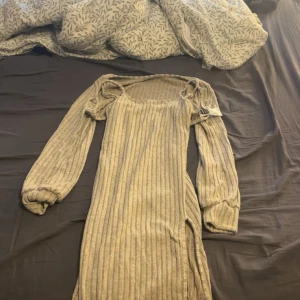Beige ribbad klänning från SHEIN - Superfin beige ribbad klänning från SHEIN i storlek M. Klänningen har långa puffärmar, rundad halsringning och en slits på sidan. Materialet är mjukt och stretchigt med inslag av polyester, elastan och viskos. Perfekt för dig som gillar en enkel men trendig look. Har aldrig använt den då den aldrig kommer till användning. 