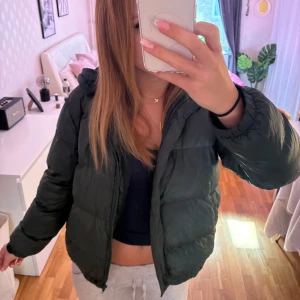 Grön pufferjacka Design By Amor - Säljer en mörkgrön pufferjacka från Design By Amor i storlek S. Jackan har huva, dragkedja framtill och är quiltad för extra värme. Perfekt för kyliga dagar och har en loose passform som ger en chill vibe.