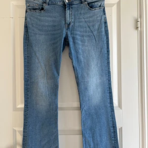 Ljusblå raka jeans med klassisk passform - Säljer ett par ljusblå jeans med raka ben och klassisk femficksdesign. Jeansen har normal midja, dragkedja och knapp framtill samt snygga kontrastsömmar. Perfekta för en avslappnad och stilren look. De har även stretch