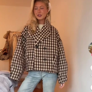 Rutig kappa - Säljer en riktigt snygg rutig kappa i brunt och vitt. Jackan har dubbelknäppning, bred krage och en oversized passform som ger en cool vibe. Perfekt höstjacka.