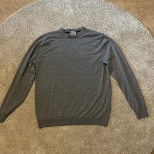 Grå merinoulltröja från Lindbergh - Snygg grå tröja från Lindbergh i mjuk merinoull. Klassisk rund halsringning, ribbade muddar och lång ärm. Perfekt för lager-på-lager och stilren look. Enkel att matcha med jeans eller chinos.