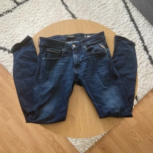 Mörkblåa Replay - Tjena👋 Säljer dessa snygga Replay Anbass jeans i mörkblå tvätt med klassisk femficksdesign och läderpatch bak🧶 Slim passform och raka ben, tillverkade i stretchigt jeansmaterial för skön komfort👖 Perfekt för dig som gillar stilrena och moderna jeans🙌 Byxorna är i Grover modell och är W30 L32