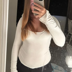 Vit långärmad topp med rund hals - Säljer en enkel och stilren vit långärmad topp med rundad halsringning från ginatricot .