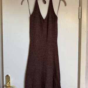 Brun ärmlös klänning med knyt - Säljer en brun klänning med snygg v-ringning. Klänningen har knyt i nacken och är ärmlös, vilket ger en cool och enkel look. Materialet är mjukt och har en lätt struktur, perfekt för varma dagar. 