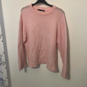 Ljusrosa stickad tröja från Lager 157 - Supermjuk  ljusrosa stickad tröja från Lager 157. Tröjan har en avslappnad passform, rund halsringning och långa ärmar. Perfekt för lager-på-lager och att mysa i under kyliga dagar.