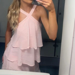 Rosa lång klänning  - Säljer en superfin ljusrosa långklänning med  volanger. Från Vila och har bara använts en gång. Den går hela vägen ner till marken på mig som är 167. Den är öppen i ryggen och har dragkedja i bak💕