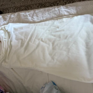 Vit långklänning med gulddetaljer - Elegant vit långklänning med smala axelband och snygga guldfärgade detaljer med hjärtan och glittrande stenar framtill. Klänningen har en mjuk och följsam känsla, perfekt för dig som vill sticka ut med en stilren look.