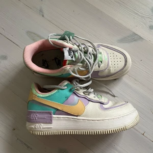 Nike Air Force Pastell  - Nike Air Force sneakers i en färgglad mix av pastellfärger: lila, mintgrön, gul, rosa och vit. Skorna har högre sula med rund tå. Använd fåtal gånger och är i mycket bra skick. Storlek 38,5