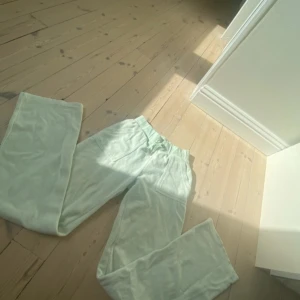 Mintgröna mjukisbyxor Juicy Couture XS - Supermjuka mintgröna mjukisbyxor från Juicy Couture med bred resår i midjan och två fickor med lock och tryckknappar bak. Perfekt för chill dagar och har en klassisk relaxed fit.