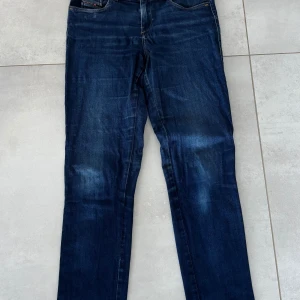 Blå Diesel D-Sandy jeans straight fit - Snygga blå jeans från Diesel, modell D-Sandy med straight fit och regular waist. Klassisk femficksdesign, mörkblå tvätt med lätt slitning och tydliga sömmar. Perfekta för dig som gillar en tidlös och clean look.