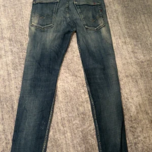 Replay jeans  - Snygga Replay jeans med klassisk tvätt och raka ben. Jeansen har fem fickor och diskreta slitningar för en avslappnad look. Perfekta för dig som gillar en tidlös stil och vill ha ett par jeans som funkar till det mesta.