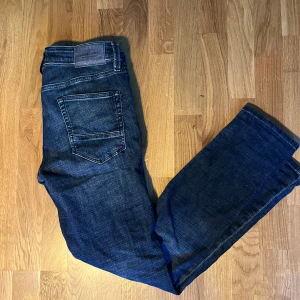 Jack & Jones Slim Glenn jeans blå - Mörkblå jeans från Jack & Jones, modell Slim Glenn. Snygg tvätt med lätt slitning och klassisk femficksdesign. Jeansen har smal passform och normal midja, perfekta för en stilren vardagslook. Materialet är mjukt och stretchigt för extra komfort.