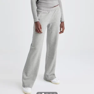 Low waist mjukis byxor - Säljer ett par gråa mjukisbyxor med breda ben och resår i midjan. Byxorna har en avslappnad passform och är tillverkade i mjukt bomullsmaterial, perfekta för chill dagar. Passar dig som gillar en loose och bekväm stil.